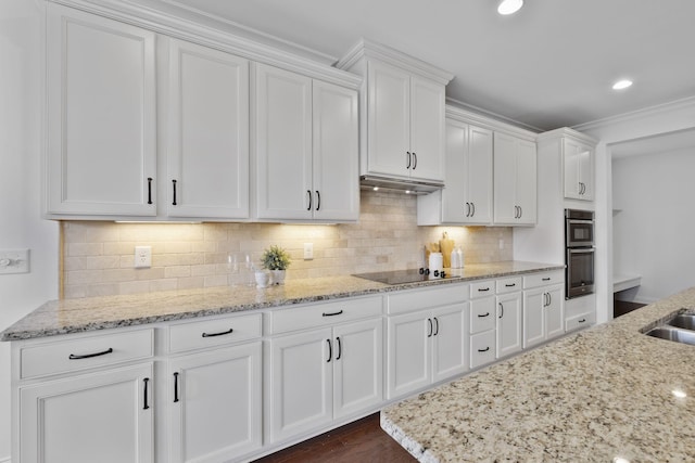 kitchen with white cabinetry, light stone counters, stainless steel double oven, black electric stovetop, and decorative backsplash