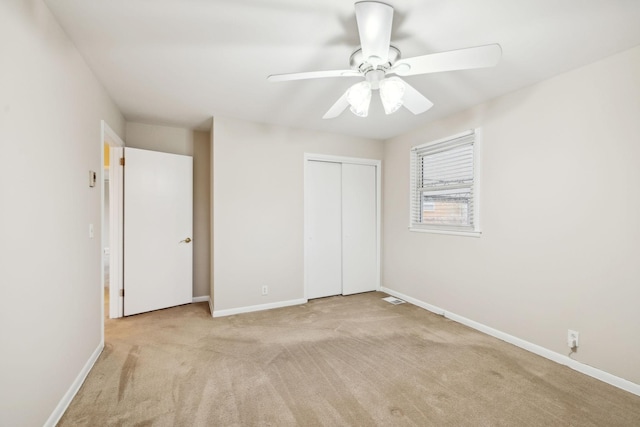 unfurnished bedroom featuring ceiling fan, a closet, and light carpet