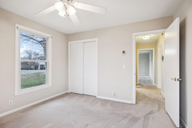 unfurnished bedroom with ceiling fan, a closet, and light carpet