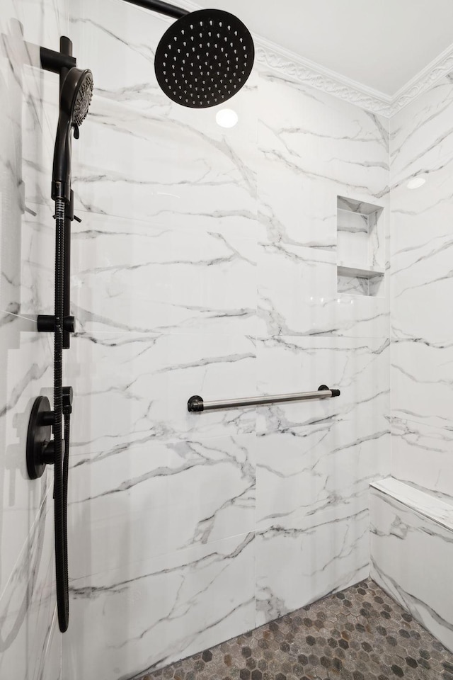 bathroom with ornamental molding and a tile shower