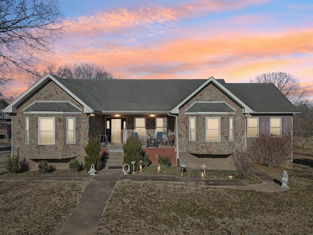 view of front of property with covered porch and a lawn