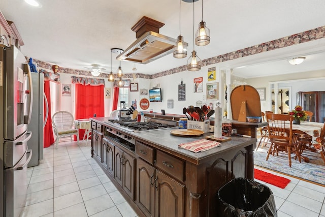 kitchen featuring dark brown cabinetry, hanging light fixtures, light tile patterned floors, and stainless steel appliances