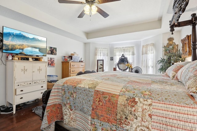 bedroom with dark hardwood / wood-style flooring, a tray ceiling, and ceiling fan