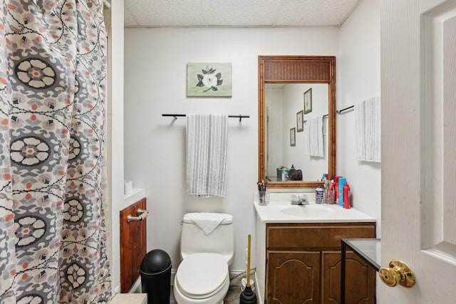 bathroom with vanity, toilet, and a drop ceiling