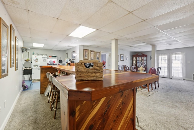 kitchen featuring carpet, white fridge with ice dispenser, and a drop ceiling