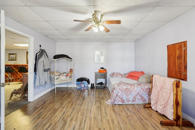 bedroom featuring a drop ceiling, hardwood / wood-style flooring, and ceiling fan