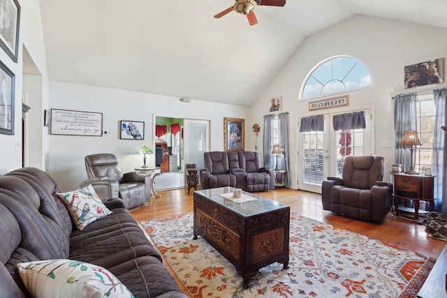 living room with ceiling fan, high vaulted ceiling, and light hardwood / wood-style flooring