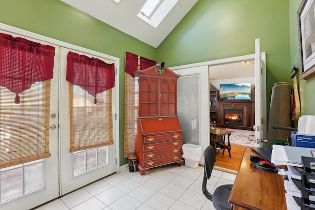 office featuring light tile patterned flooring, vaulted ceiling with skylight, and french doors