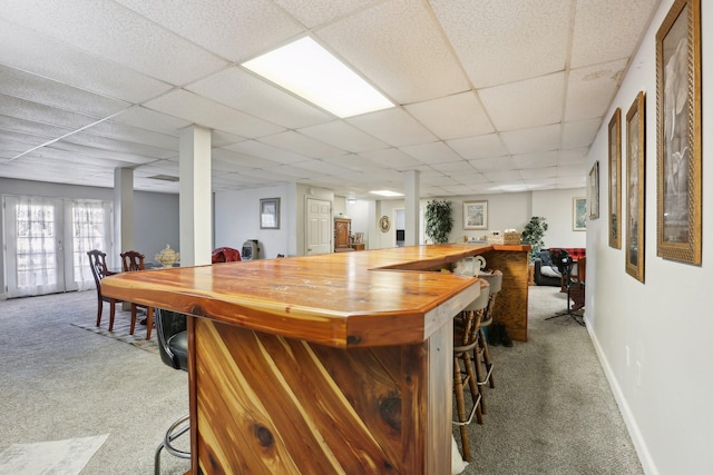 bar featuring wood counters, a paneled ceiling, and light colored carpet