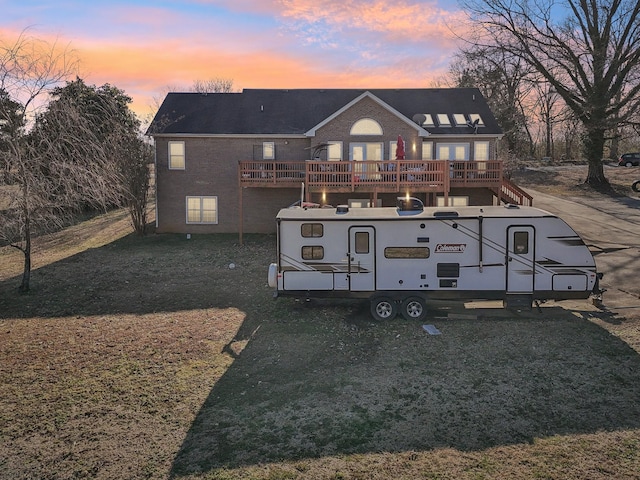 back house at dusk featuring a yard and a deck