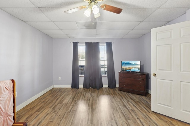 spare room with a drop ceiling, wood-type flooring, and ceiling fan