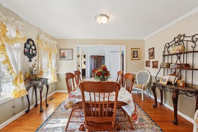 dining area with crown molding and light hardwood / wood-style floors