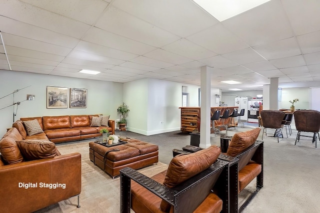 living room featuring a community bar, baseboards, a drop ceiling, and light carpet