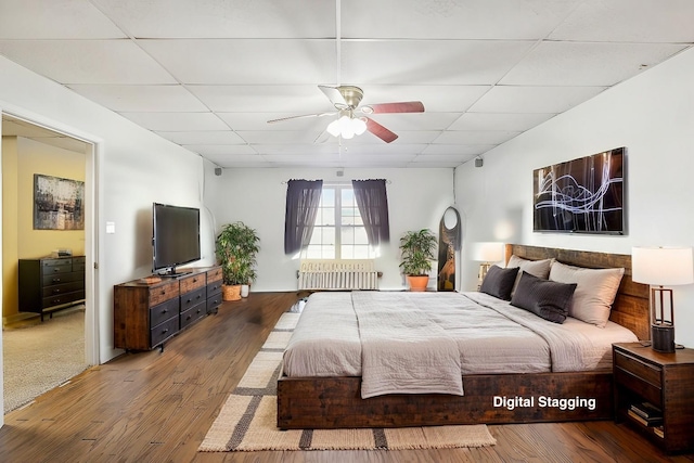 bedroom with a drop ceiling, ceiling fan, and wood finished floors