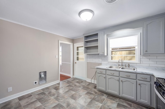 kitchen with open shelves, light countertops, gray cabinetry, stainless steel range oven, and a sink