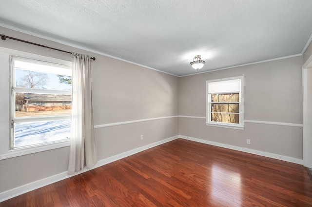 spare room with crown molding, dark wood finished floors, a textured ceiling, and baseboards