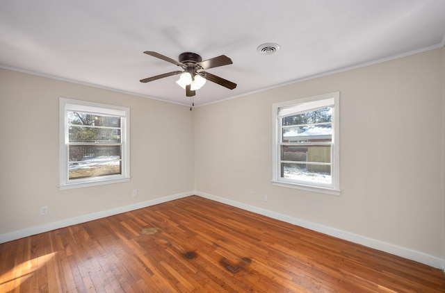 empty room featuring crown molding, wood finished floors, visible vents, and baseboards