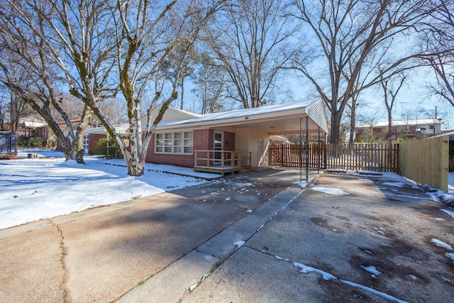 view of front of home featuring driveway, brick siding, fence, and an attached carport