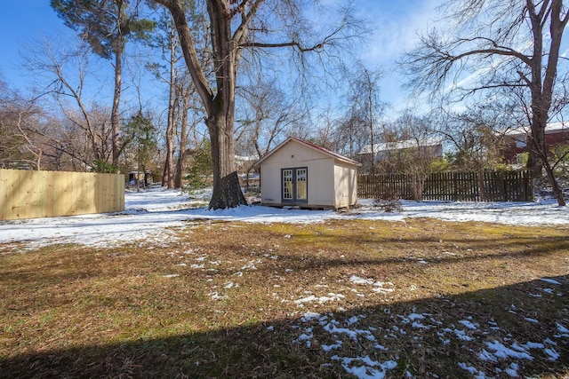 yard layered in snow featuring an outbuilding and fence