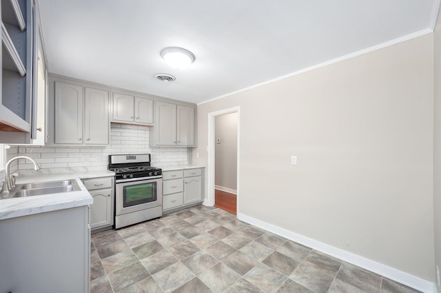 kitchen with stainless steel gas range, gray cabinets, light countertops, and a sink