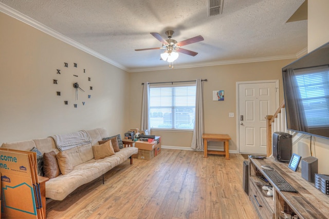 living room featuring ceiling fan, ornamental molding, light hardwood / wood-style floors, and a textured ceiling