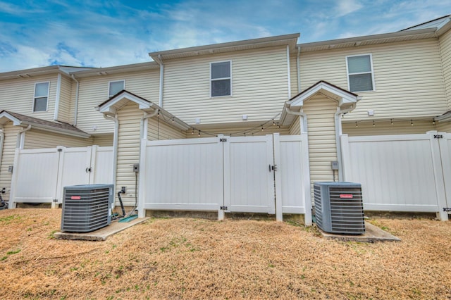 back of house featuring a lawn and central air condition unit