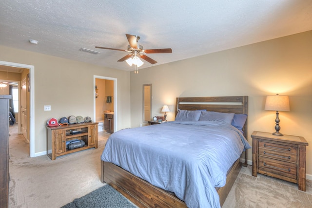 carpeted bedroom featuring ceiling fan, a textured ceiling, and ensuite bath