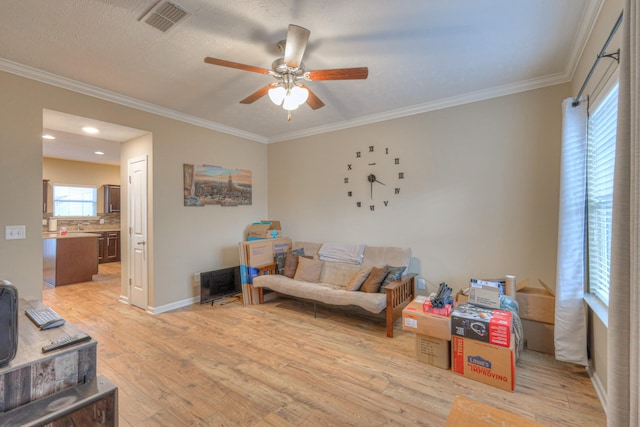 living room with light hardwood / wood-style flooring, ornamental molding, and ceiling fan