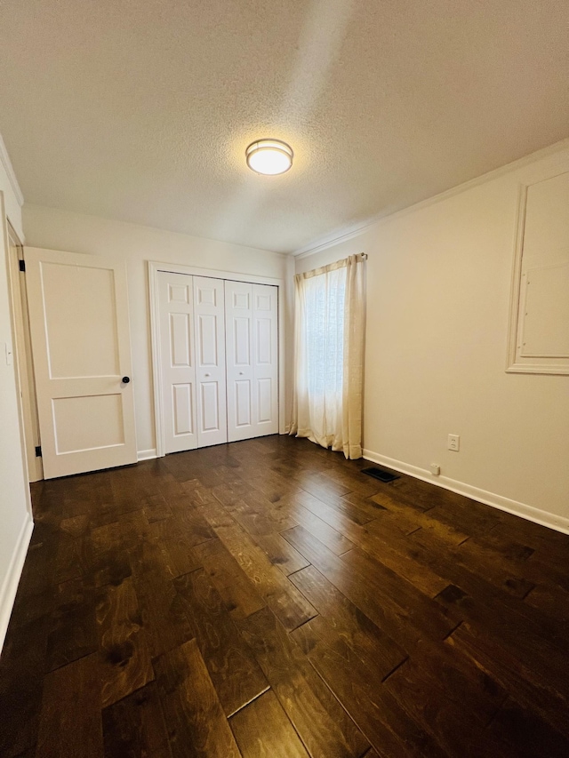 unfurnished bedroom with a closet, dark hardwood / wood-style flooring, and a textured ceiling