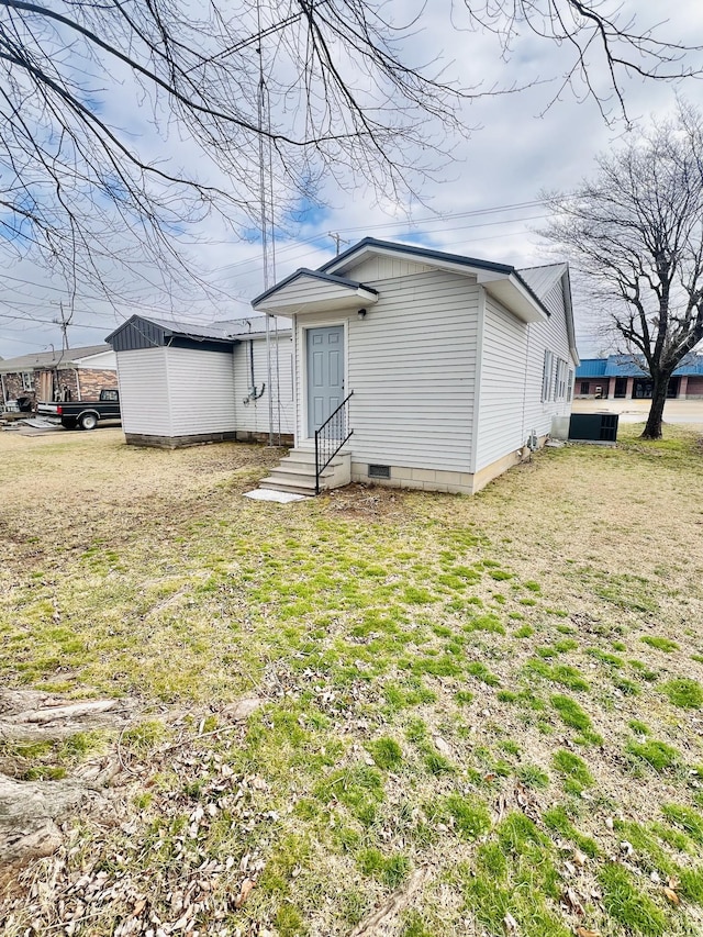 rear view of property featuring a lawn and central air condition unit