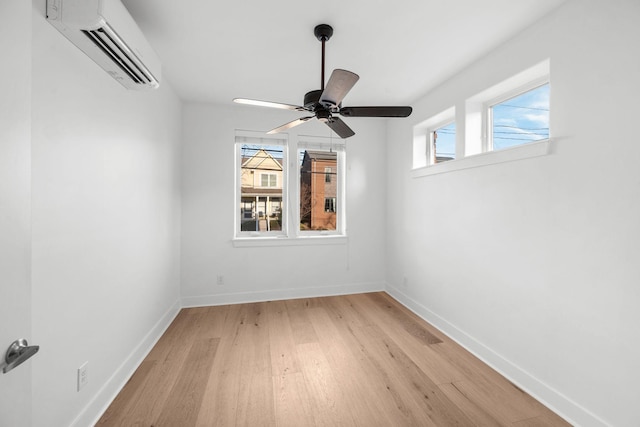 unfurnished room with ceiling fan, a wall mounted AC, and light hardwood / wood-style flooring