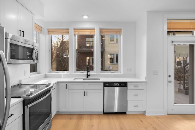 kitchen featuring white cabinetry, stainless steel appliances, sink, and light hardwood / wood-style flooring