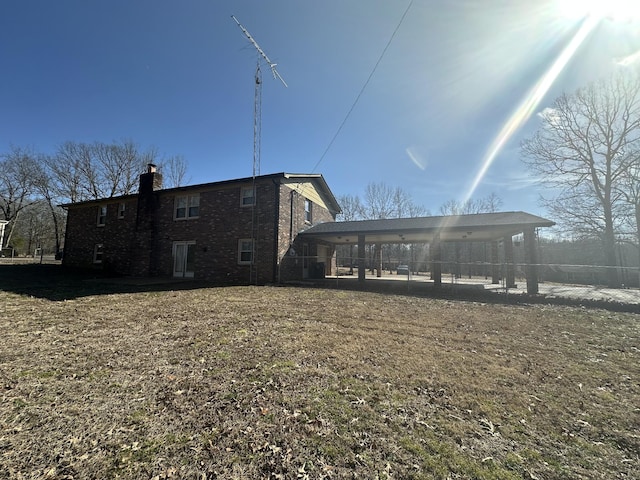 rear view of house featuring a carport and a lawn