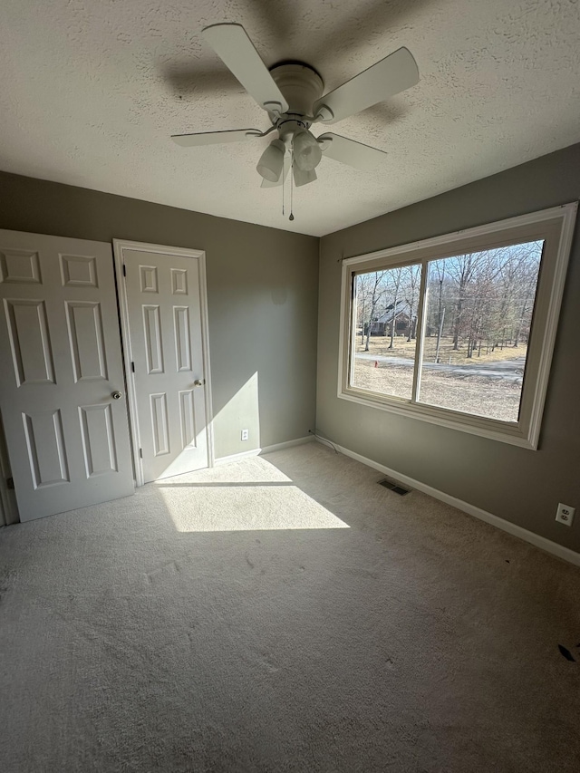 unfurnished bedroom featuring ceiling fan, carpet floors, and a textured ceiling