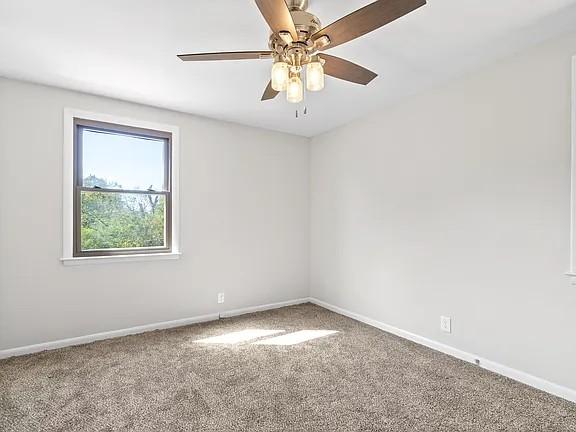 carpeted spare room with ceiling fan