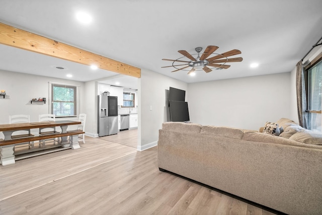 living room with ceiling fan, beam ceiling, and light hardwood / wood-style floors