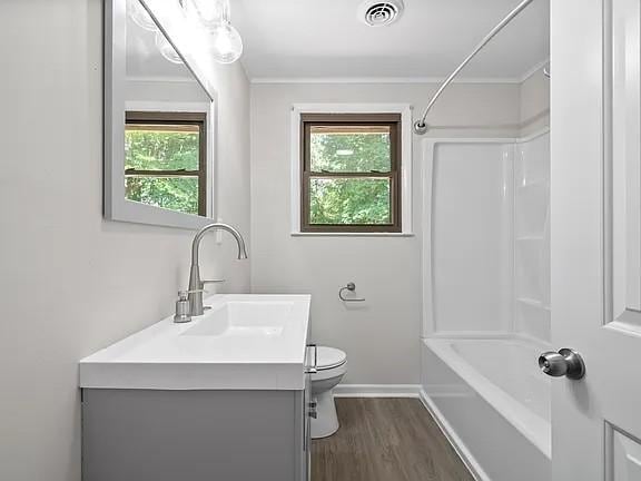 full bathroom featuring vanity, toilet, hardwood / wood-style floors, and plenty of natural light