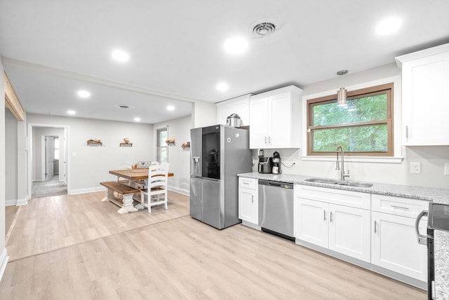 kitchen with stainless steel appliances, sink, white cabinets, and light wood-type flooring