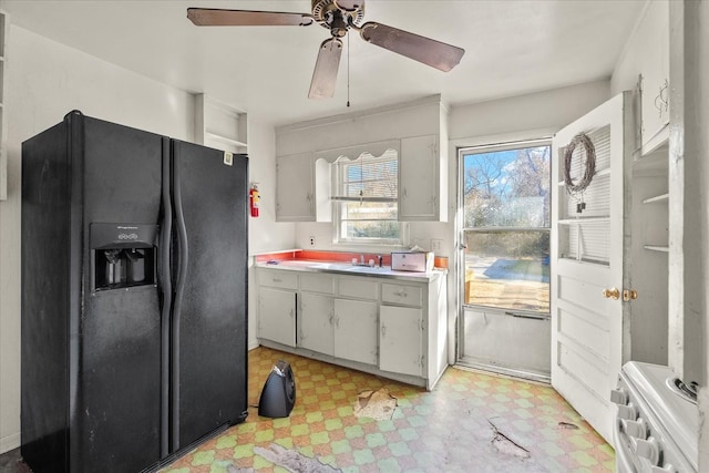 kitchen with white cabinetry, ceiling fan, and black fridge