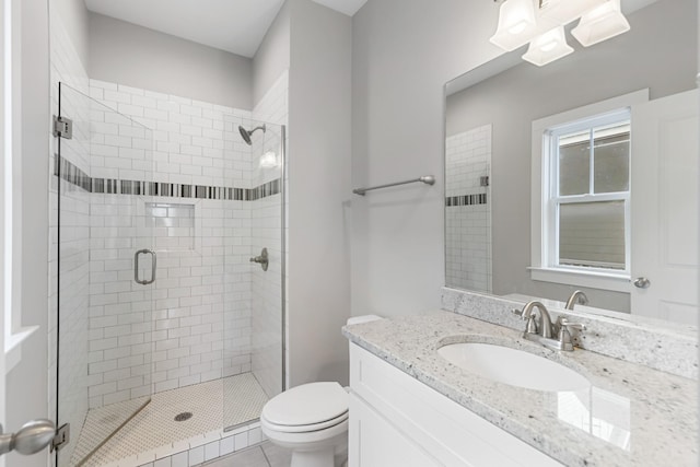 bathroom with tile patterned floors, vanity, toilet, and a shower with door