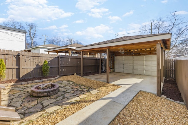 view of patio with a garage, an outbuilding, a carport, and an outdoor fire pit