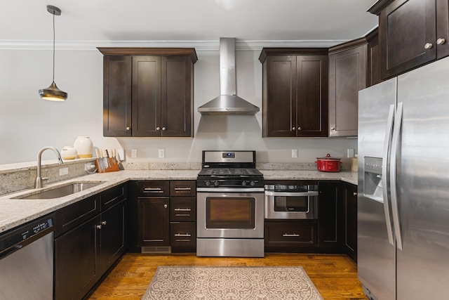 kitchen with appliances with stainless steel finishes, pendant lighting, sink, light stone countertops, and wall chimney range hood