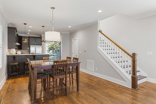 dining space with ornamental molding and dark hardwood / wood-style floors