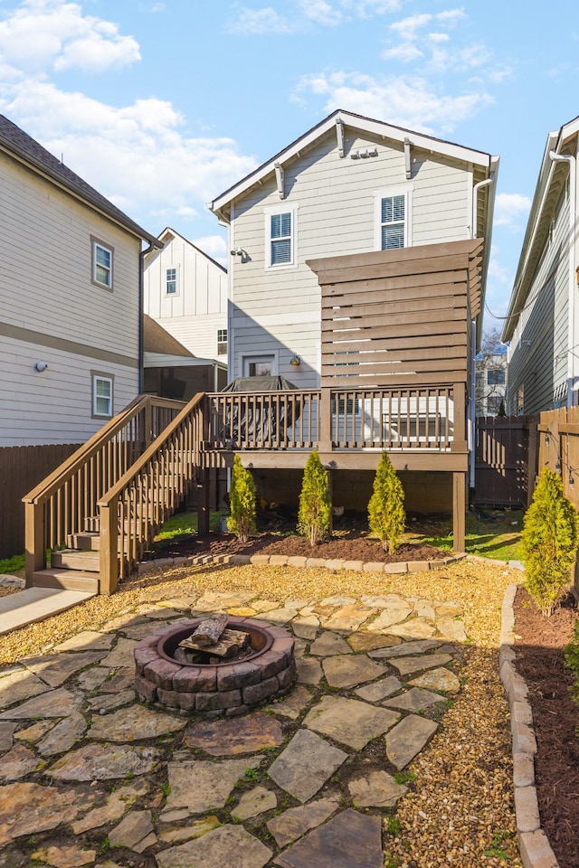 rear view of property featuring a deck and a fire pit