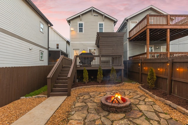 back house at dusk featuring a wooden deck and an outdoor fire pit