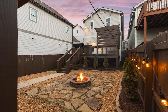 back house at dusk featuring a fire pit, a patio area, and a deck