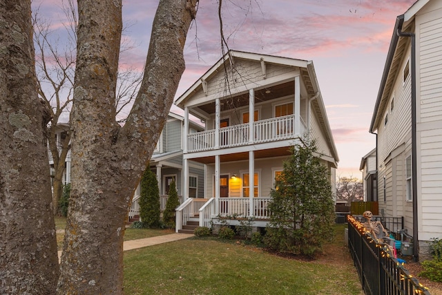 view of front of house with a porch, a balcony, and a lawn