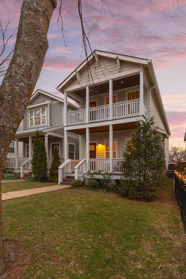 view of front facade featuring a balcony, a porch, and a lawn