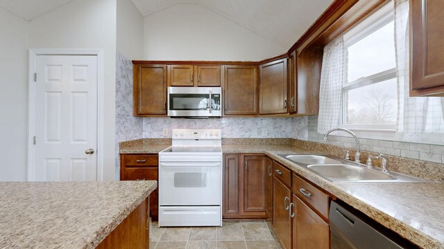 kitchen featuring lofted ceiling, stainless steel appliances, sink, and backsplash