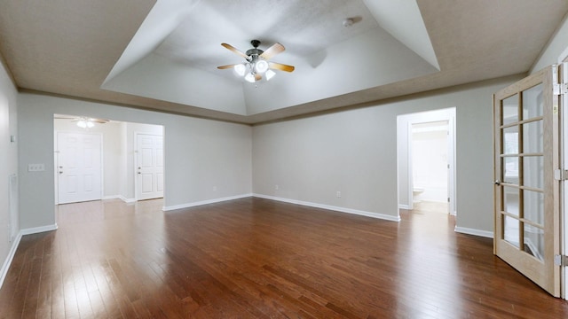 spare room featuring a raised ceiling, ceiling fan, and dark hardwood / wood-style flooring